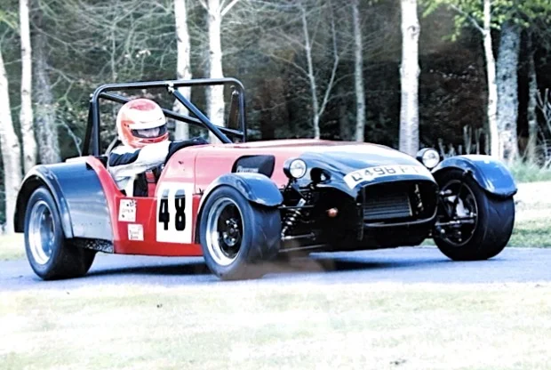 Red and black Caterham Seven number 48 on dusty hillclimb stage