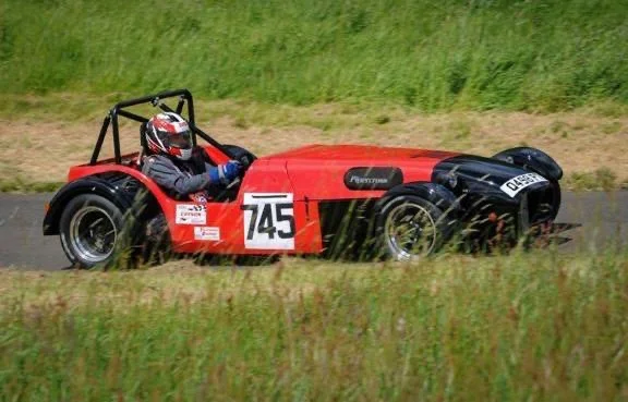 Red Caterham Seven number 745 climbing a grass-banked hillclimb
