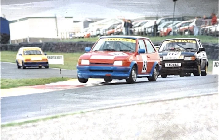 Red and blue hatchback number 69 leading the pack in wet circuit race